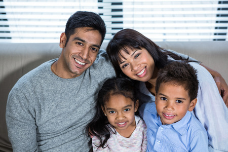 Happy young family posing together on the couch in living room