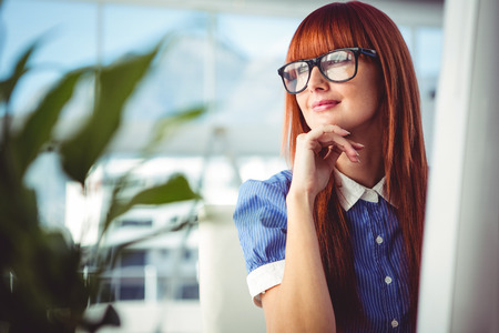 Attractive smiling hipster woman thinking in her officeの写真素材