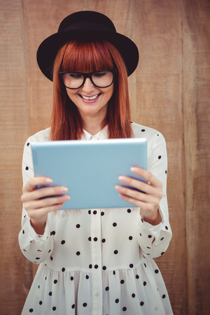 Smiling hipster woman using her tablet against wooden backgroundの写真素材