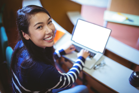 Happy student in lecture hall using laptop at the universityの写真素材