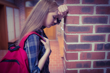 Worried student leaning against the wall at the universityの写真素材