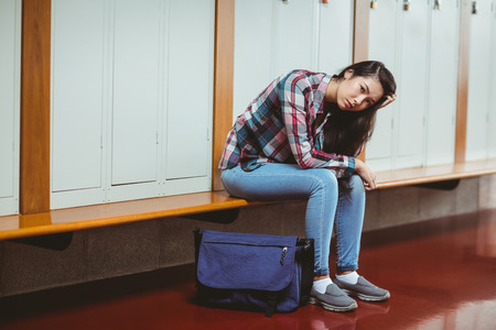 Worried student sitting with hand on head at the universityの写真素材