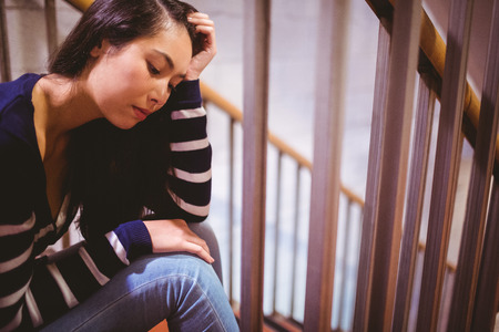 Worried student sitting in hallway at the universityの写真素材