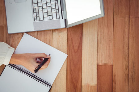 Cropped image of woman writing on notepad in her officeの写真素材