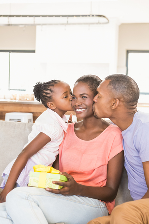 Father and his daughter offering a gift in living roomの写真素材