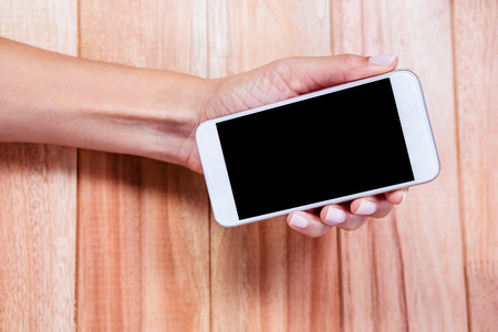 Overhead of feminine hand holding smartphoneの写真素材