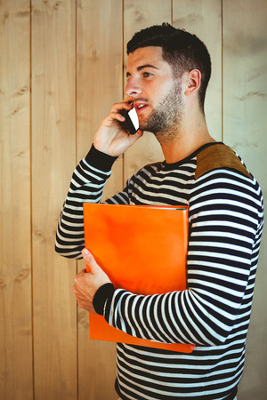 Casual hipster using his phone on wooden backgroundの写真素材