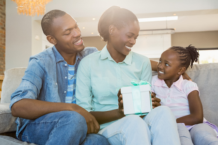 Pretty couple offer a present for their daughter in living roomの写真素材