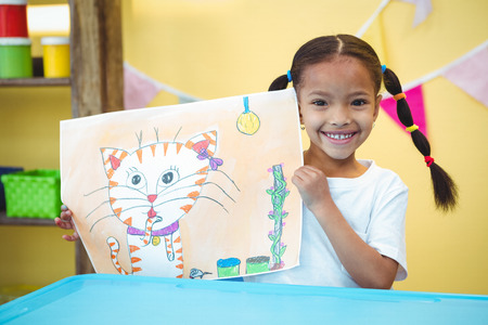 Smiling girl with a painting of her cat at the deskの写真素材