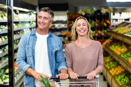Smiling bright couple buying food products at supermarketの写真素材