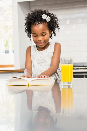 Smiling girl reading a book in the kitchenの写真素材