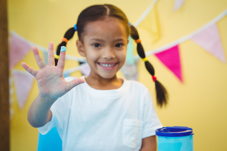Girl smiling with paint on her finger at the deskの写真素材