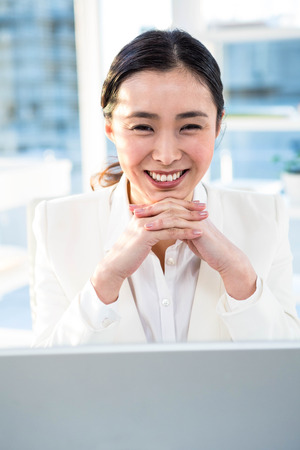 Smiling businesswoman looking at the camera at the desk in workの写真素材
