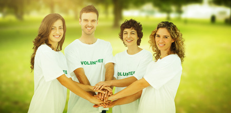 Smiling volunteer group piling up their hands against park