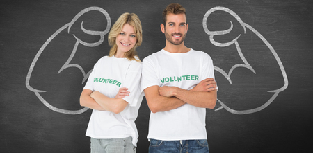 Portrait of two happy volunteers with hands crossed against black backgroundの写真素材