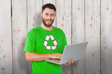 Portrait of man working on laptop in office against wooden backgroundの写真素材