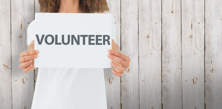 Volunteer showing a poster against wooden backgroundの写真素材
