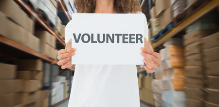 Volunteer showing a poster against shelves with boxes in warehouseの写真素材