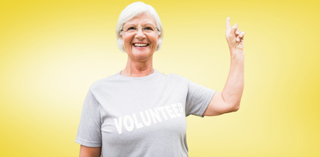 Happy volunteer grandmother with thumbs up  against yellow vignetteの写真素材