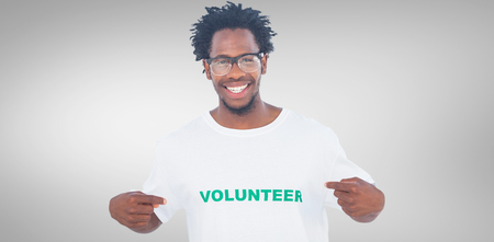 Handsome man pointing to his volunteer tshirt against grey vignetteの写真素材