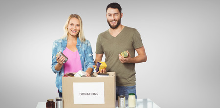 Portrait of happy colleagues smiling while holding products  against grey vignette