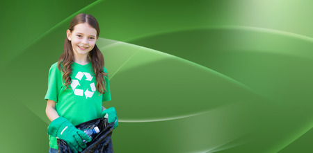 Happy little girl collecting rubbish  against abstract green designの写真素材