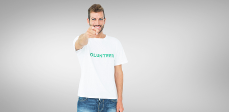 Portrait of a happy male volunteer pointing at you against grey vignetteの写真素材
