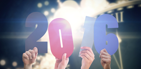Hands showing 2016 against black and gold new year graphic