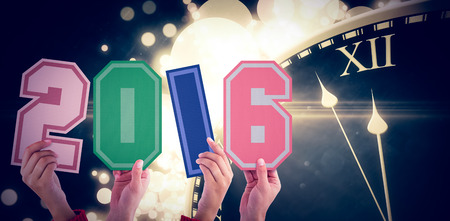 Hands showing 2016 against black and gold new year graphicの写真素材