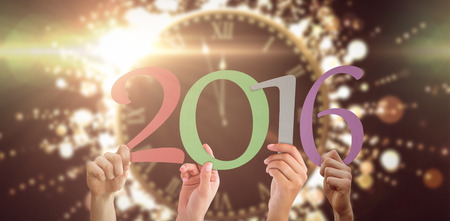 Hands showing 2016 against clock counting down to midnightの写真素材