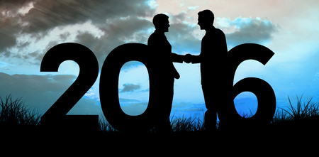 Silhouettes shaking hands against blue sky over grass