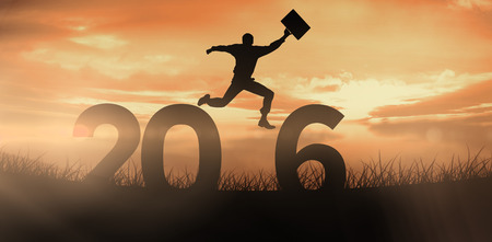 Businessman jumping with briefcase against red sky over grassの写真素材