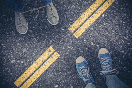 Low section of man with shoelaces tied together  against roadの写真素材