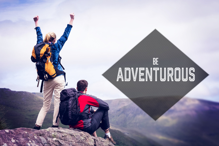 Motivational new years message against excited couple reaching the top of their hike