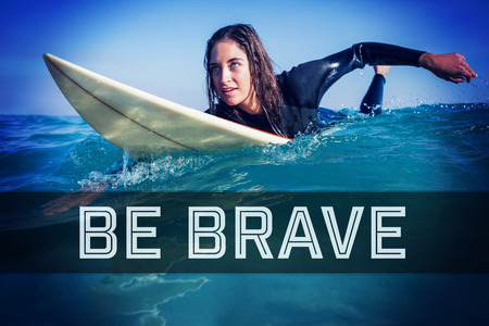 Motivational new years message against woman in wetsuit with a surfboard on a sunny dayの写真素材