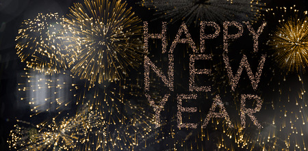 Glittering happy new year against colourful fireworks exploding on black background