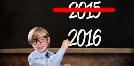 Cute pupil writing against blackboard on wallの写真素材