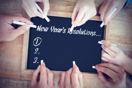 New years resolution list against hands writing on chalkboardの写真素材
