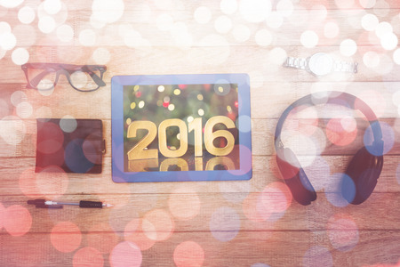 Close-up of golden 2016 against illuminated Christmas tree against close up view of business stuff