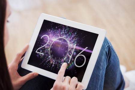 Teen using a tablet pc sitting on the floor against new year countdown graphicの写真素材