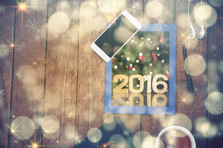 Golden 2016 against illuminated Christmas tree against close up view of business stuff