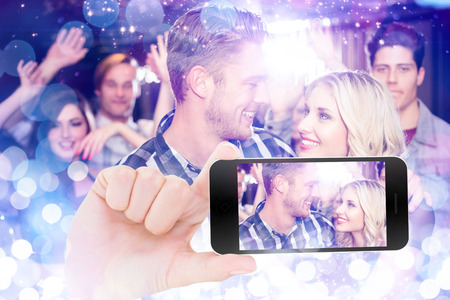 Female hand holding a smartphone against glowing backgroundの写真素材