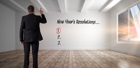 Businessman in suit pointing finger against empty white room