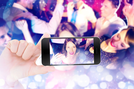 Female hand holding a smartphone against glowing backgroundの写真素材