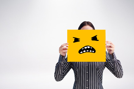 Smiling woman showing a big business card in front of her face against white background with vignetteの写真素材