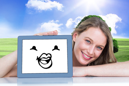 Woman showing tablet pc  against wooden floor against fieldの写真素材