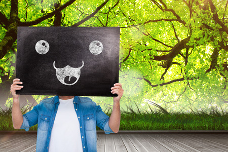 Casual man showing board against wooden floor against forestの写真素材