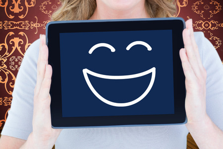 Portrait of happy woman showing digital tablet  against room with wallpaperの写真素材
