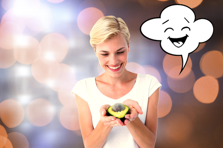 Attractive woman holding fresh avocado against glowing backgroundの写真素材