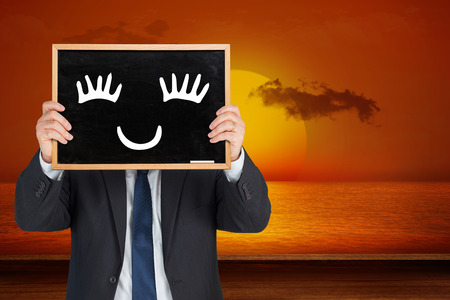 Businessman showing board against wooden planks against sunsetの写真素材